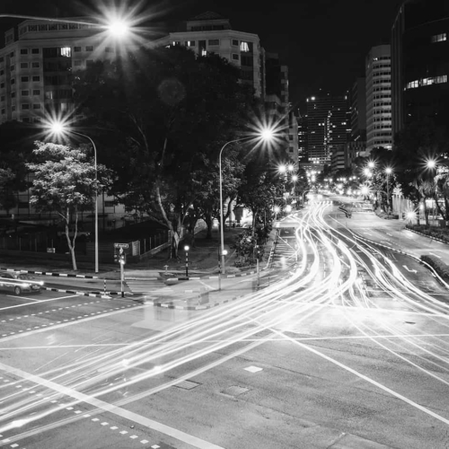 Black and white image of busy traffic intersection at night.